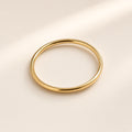 Bague Trait de Plume, finition dorée sur argent 925, anneau rond, lisse et très fin, sans pierre, sur fond crème