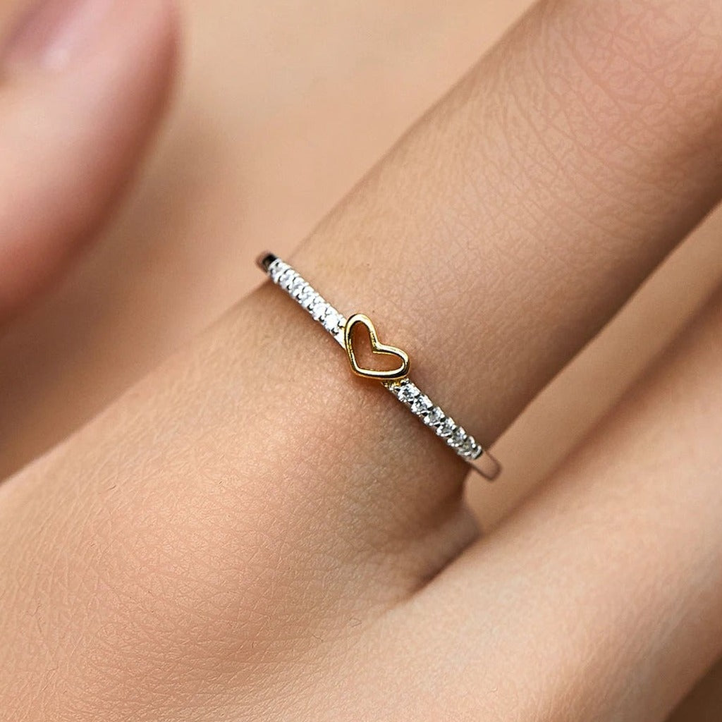 Bague Clin d'Œil portée au doigt : le petit cœur ajouré doré sur l'anneau serti