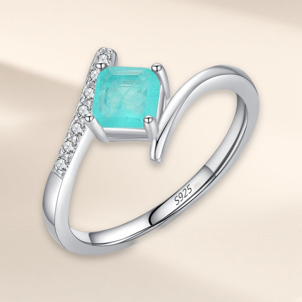 Bague Calanque vue de trois quarts : pierre carrée bleu-vert et ligne de petites pierres claires sur l'anneau croisé