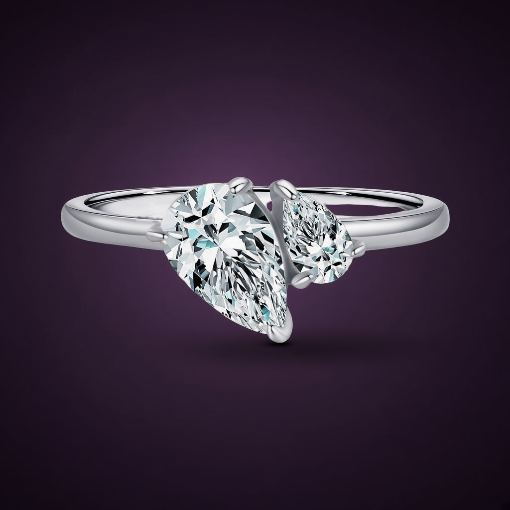 Bague Giboulée argent 925, deux zirconiums cubiques incolores taillés en goutte, un grand et un petit, posés tête-bêche sur un anneau fin, sur fond aubergine