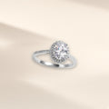 Bague Facettes argent 925, forme ovale : zirconium cubique incolore ovale dans un entourage de petites pierres, sur fond crème