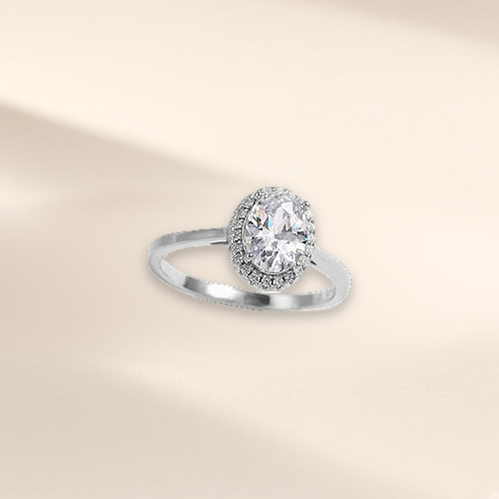 Bague Facettes argent 925, forme ovale : zirconium cubique incolore ovale dans un entourage de petites pierres, sur fond crème