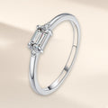 Bague Sentier argent 925, modèle pierre incolore : une pierre d'imitation rectangulaire posée dans le sens de l'anneau, un petit zirconium cubique de chaque côté, sur fond crème