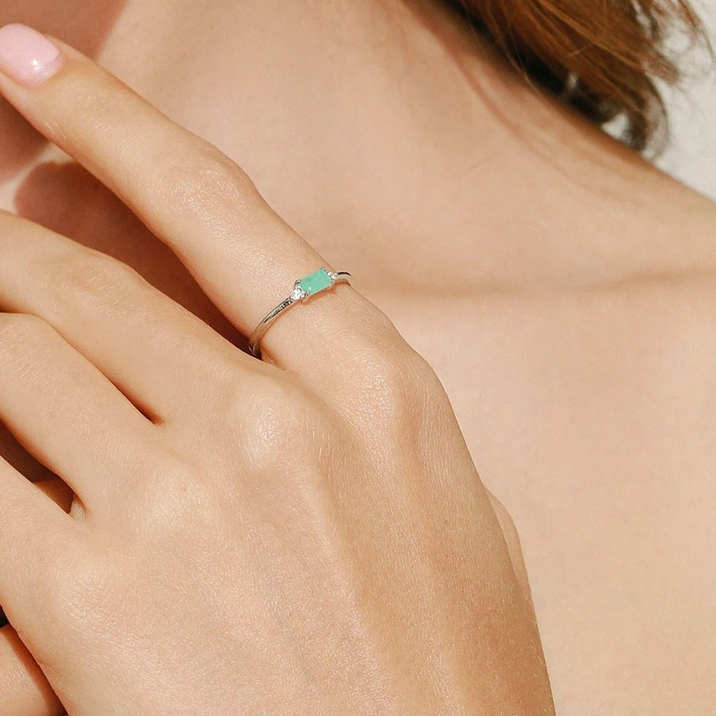 Bague Sentier portée au doigt : l'anneau fin et sa petite pierre rectangulaire verte