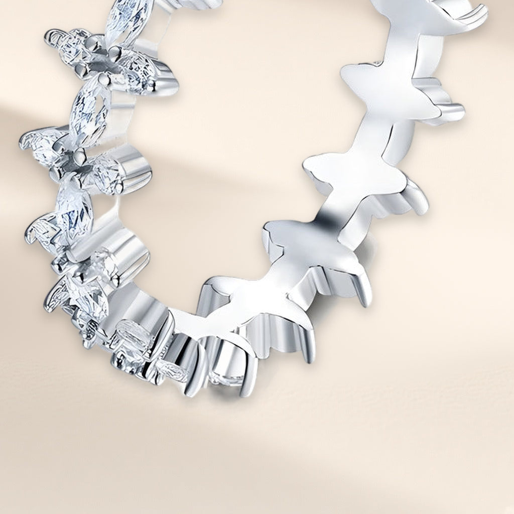 Bague Florilège vue de biais : ronde de petites fleurs en pierres navette claires, revers ajouré