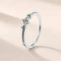 Bague Menthe à l'Eau argent 925, modèle trois pierres : zirconium cubique incolore entre deux pierres bleu-vert, sur fond crème
