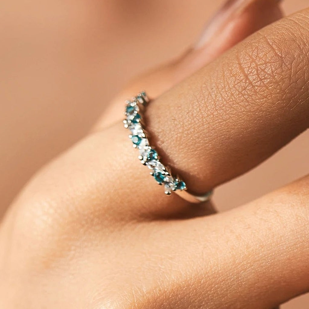 Bague Menthe à l'Eau portée au doigt : la rangée de pierres bleu-vert et claires