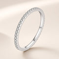 Bague Semis argent 925, modèle pierres incolores : un rang de petits zirconiums cubiques ronds serrés le long d'un anneau très fin, sur fond crème