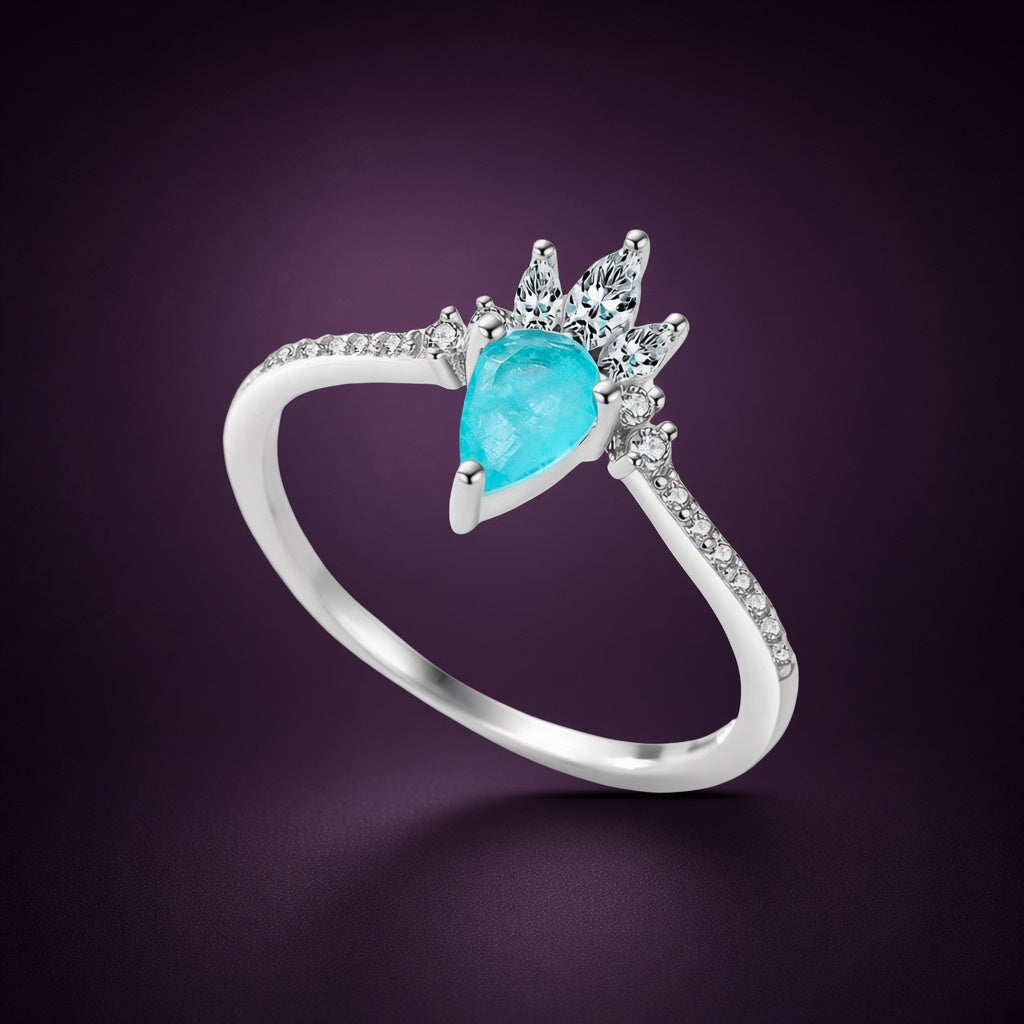 Bague Fontaine argent 925, goutte bleu-vert en pierre d'imitation sous une couronne de pierres claires, sur fond aubergine