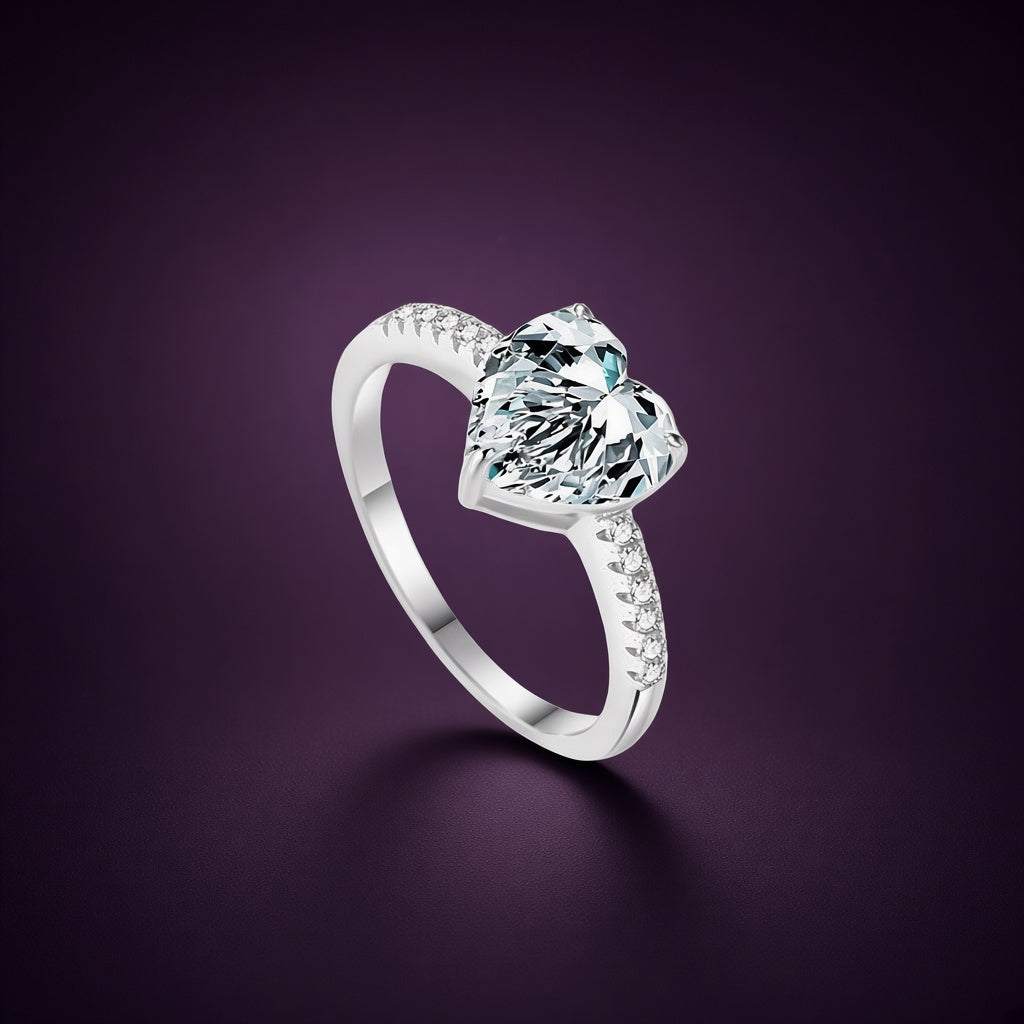 Bague Magnolia argent 925, grand cœur incolore en zirconium cubique tenu haut par des griffes, petites pierres claires sur l'anneau, sur fond aubergine