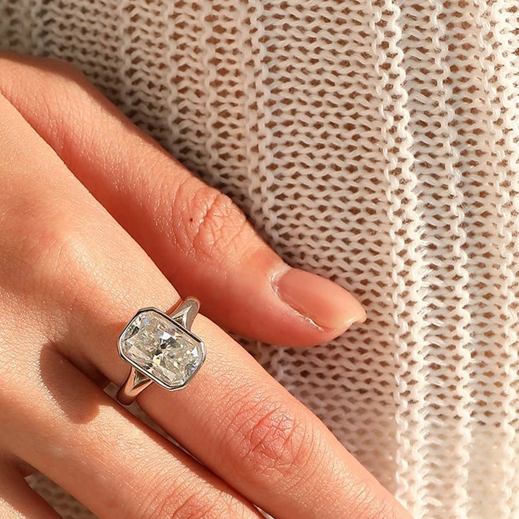 Bague Glacier portée au doigt : la grande pierre rectangulaire, main posée sur un pull en maille