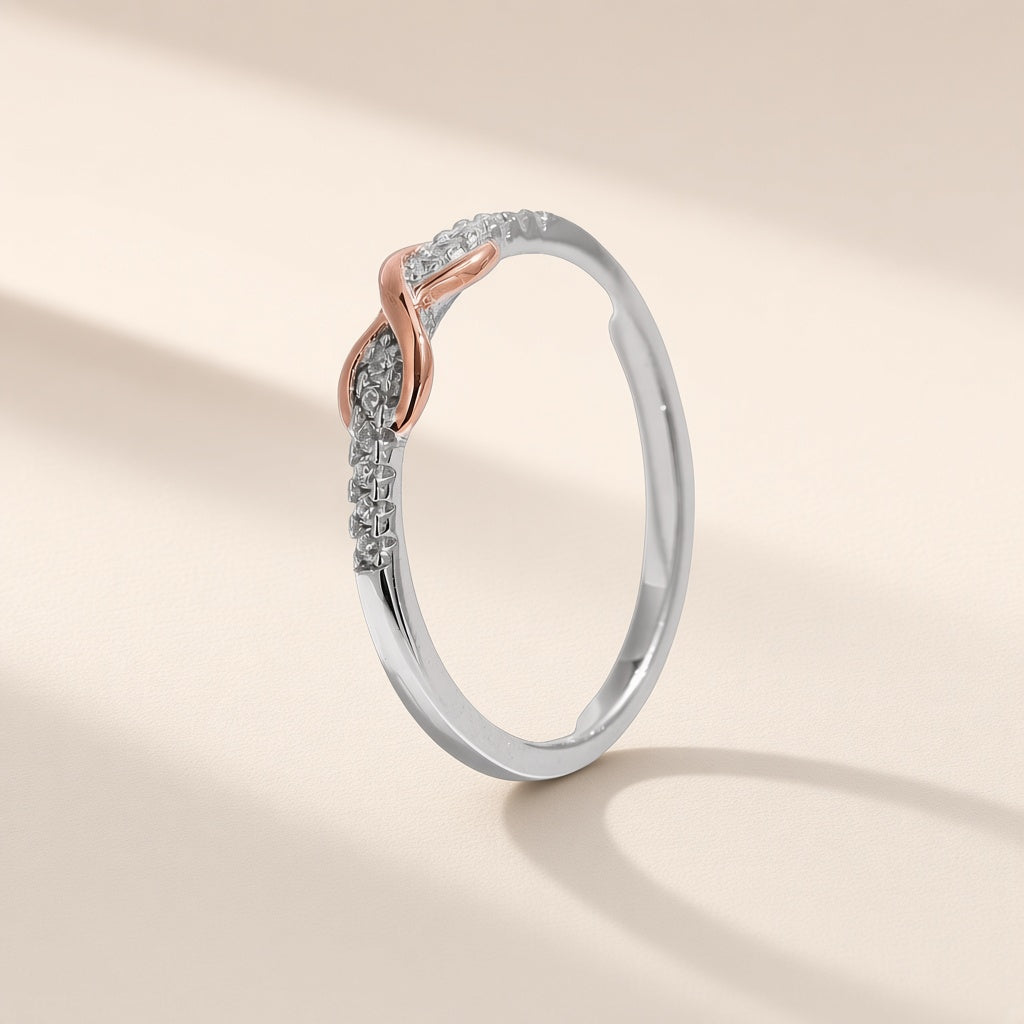 Bague Entrelacs argent 925, signe infini à finition dorée rose entre deux rangées de petits zirconiums cubiques clairs, sur fond crème