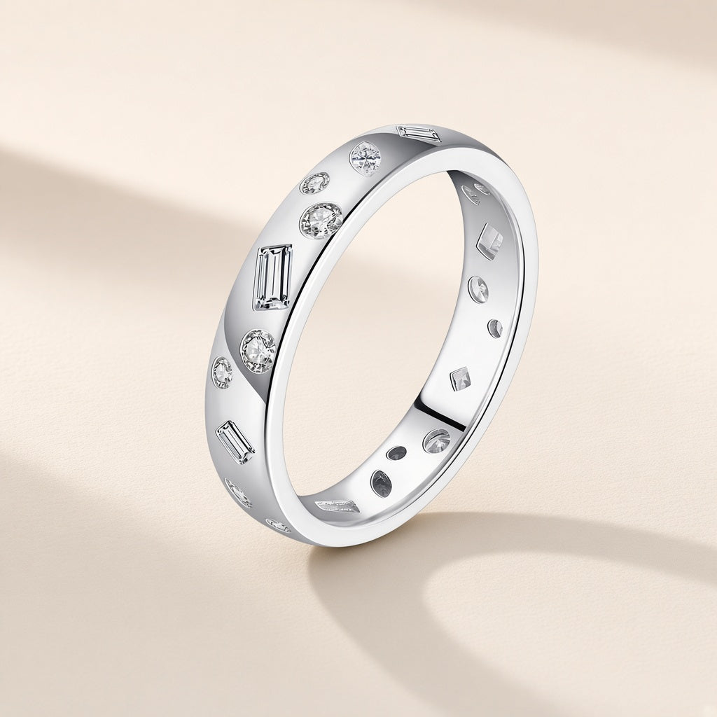 Bague Mosaïque argent 925, un anneau large et poli semé de petits zirconiums cubiques ronds, rectangulaires et en losange, sertis dans le métal, sur fond crème