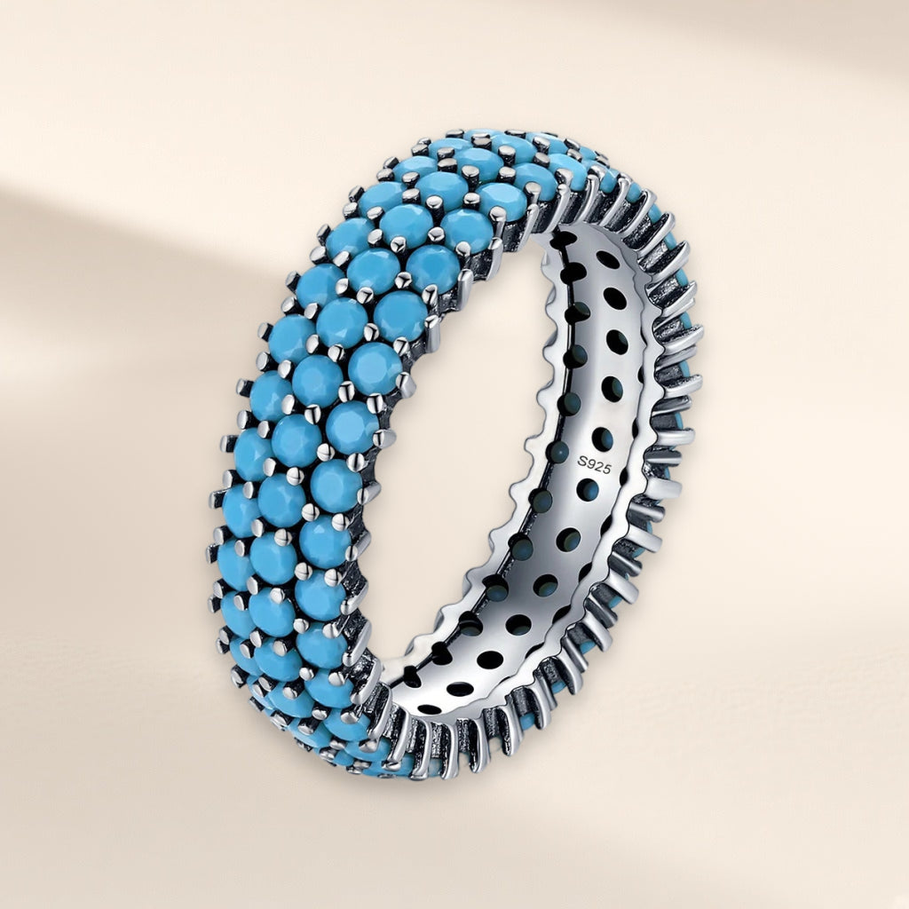 Bague Céleste vue de biais : anneau large couvert de trois rangs de petites pierres bleu turquoise