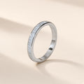 Bague Persienne argent 925, rangée de petites moissanites synthétiques rectangulaires entre deux bords de métal lisses, sur fond crème