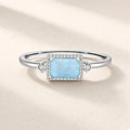 Bague Estampe argentée : pierre rectangulaire bleu pâle irisée dans un cadre perlé, une petite pierre claire de chaque côté