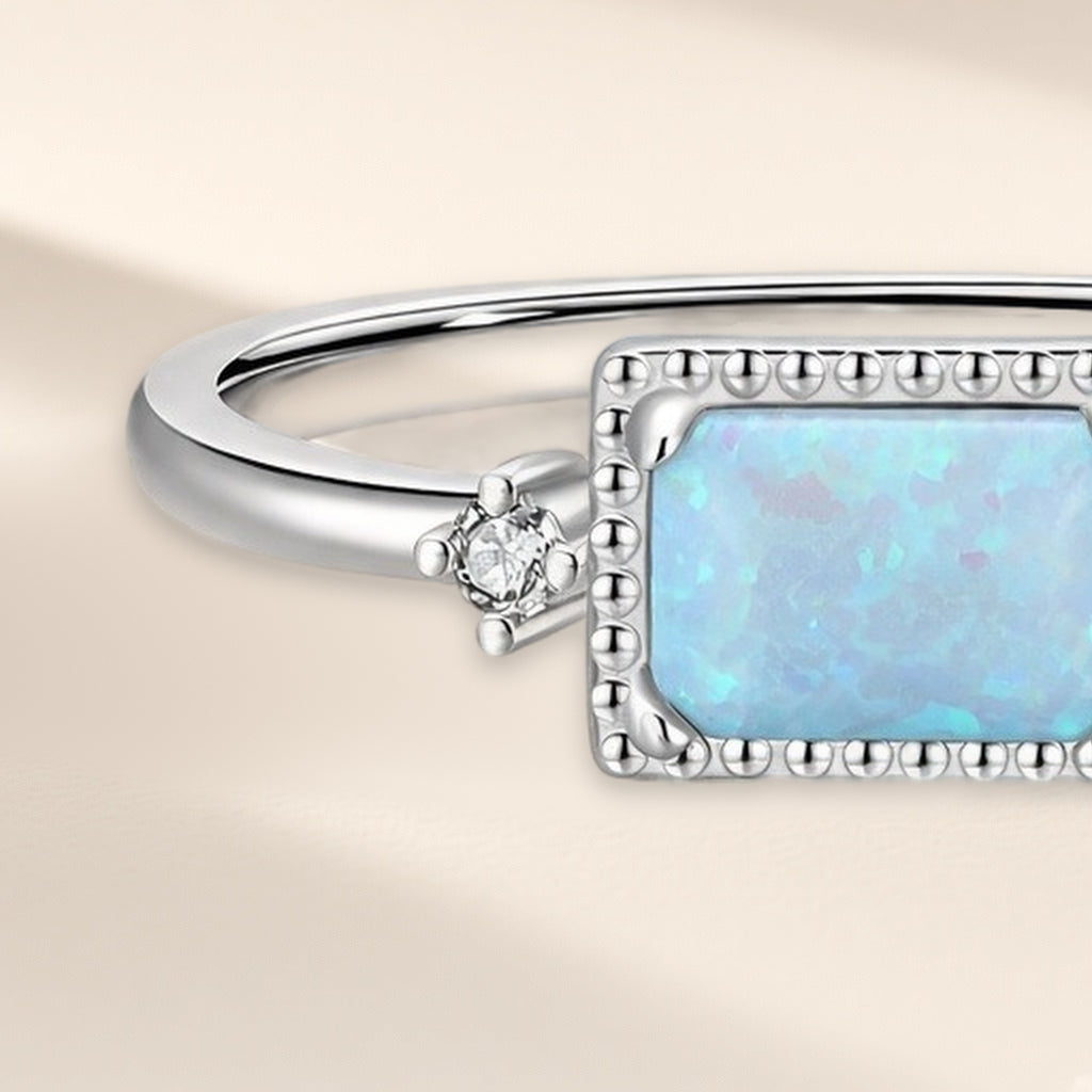 Bague Estampe en gros plan : le cadre perlé, les reflets de la pierre bleu pâle et la petite pierre claire