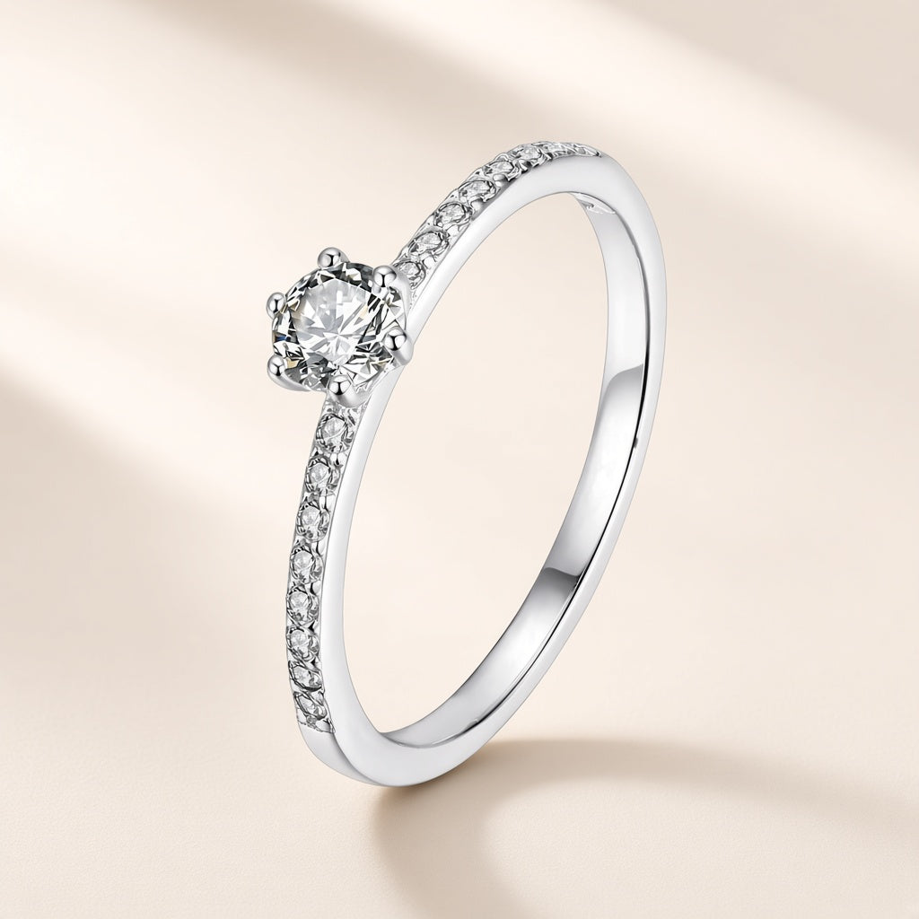 Bague Clarté argent 925, un zirconium cubique rond et incolore tenu haut par six griffes, de petits zirconiums cubiques sertis sur l'anneau de chaque côté, sur fond crème