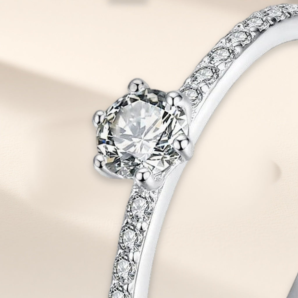 Bague Clarté en gros plan : pierre ronde claire tenue par six griffes, petites pierres sur l'anneau