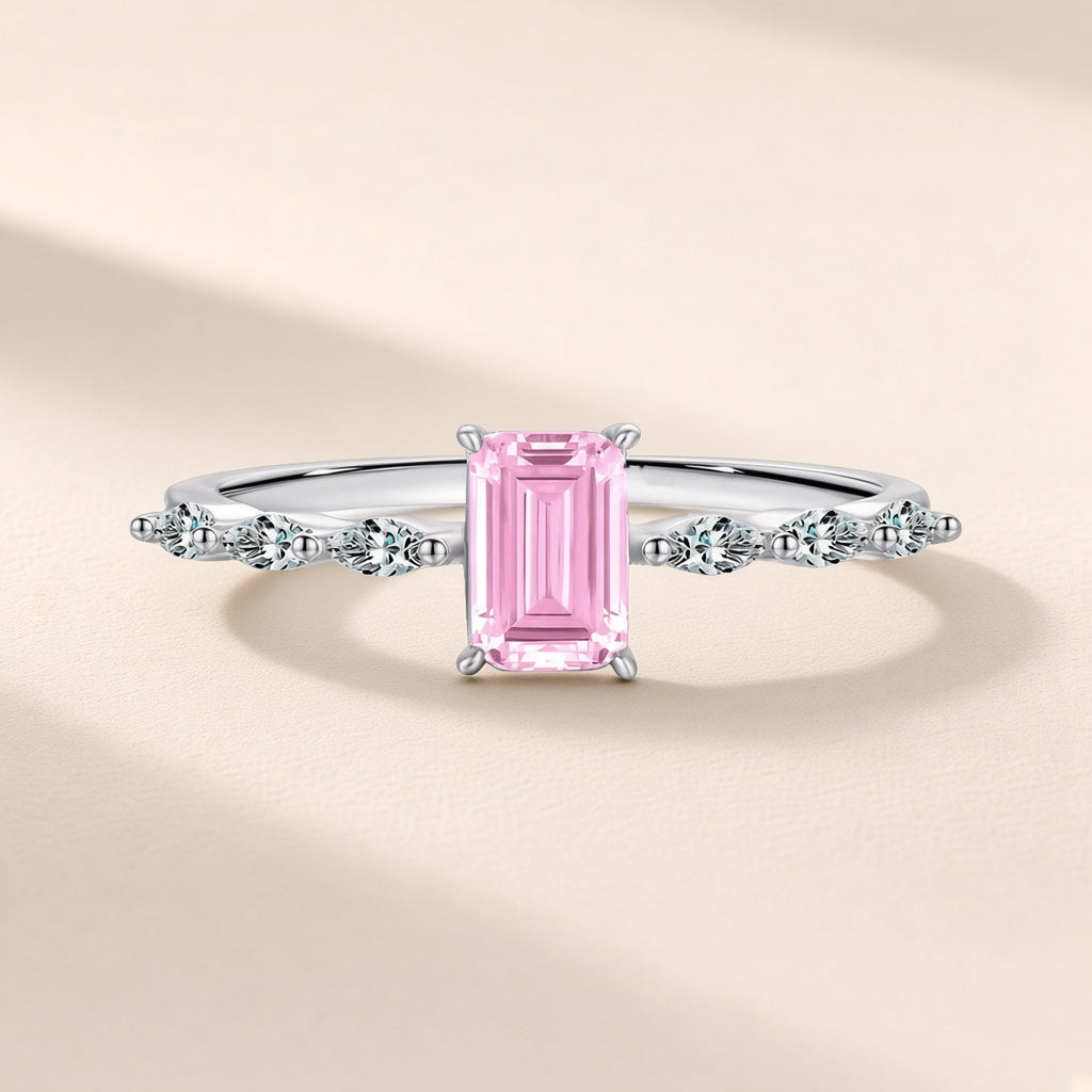 Bague Aquarelle argent 925, modèle rose : un zirconium cubique rose rectangulaire aux angles coupés, trois petites pierres d'imitation en navette de chaque côté, sur fond crème