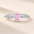 Bague Aquarelle argent 925, modèle rose : un zirconium cubique rose rectangulaire aux angles coupés, trois petites pierres d'imitation en navette de chaque côté, sur fond crème