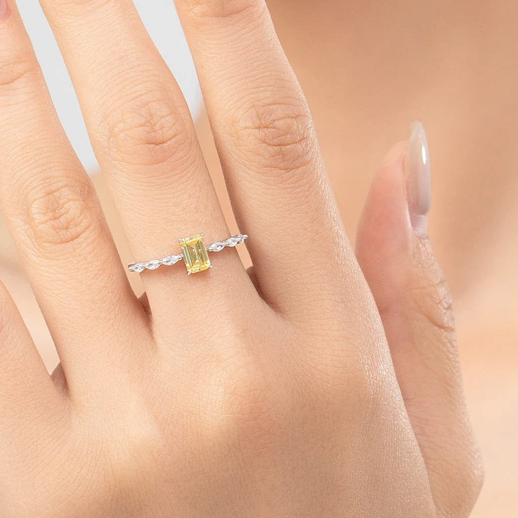 Bague Aquarelle portée au doigt : la pierre rectangulaire jaune et ses petites pierres de chaque côté