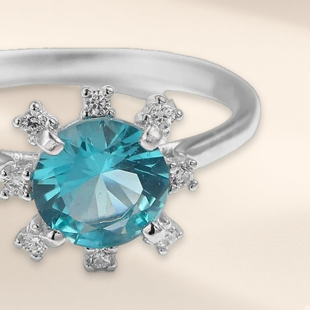 Bague Atoll en gros plan : pierre ronde bleu-vert entourée de petites pierres claires