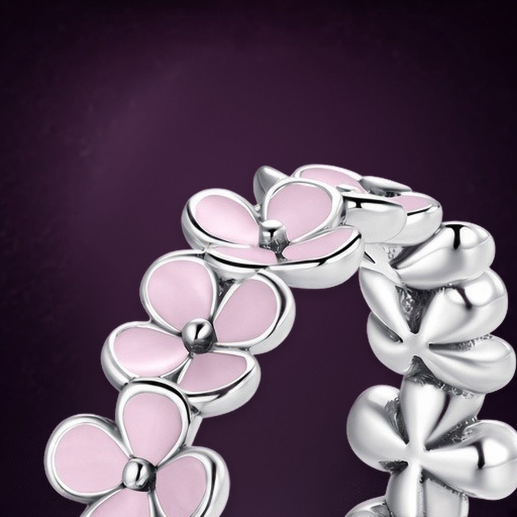 Bague Ronde des Prés en gros plan : fleurs à cinq pétales roses au cœur en relief, à côté des fleurs lisses