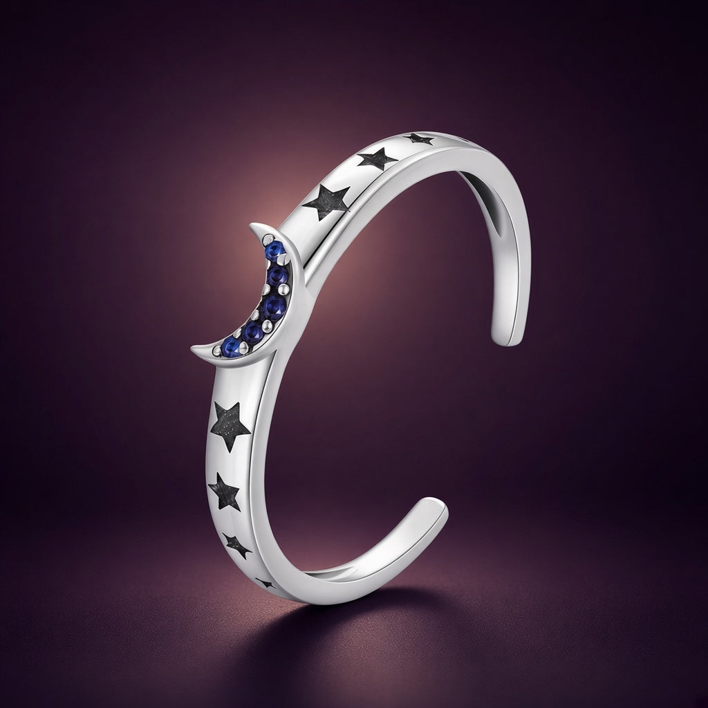 Bague lune « Éclipse » ouverte en argent 925 : anneau fin, croissant pavé de zirconiums cubiques bleus et étoiles gravées, sur fond aubergine