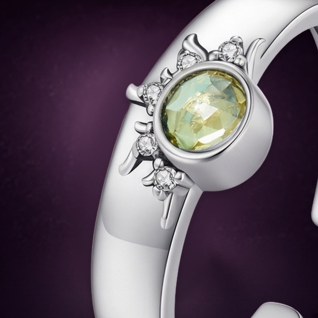Bague soleil « Éclipse » en gros plan : pierre ronde jaune-vert entourée de rayons et de petites pierres claires