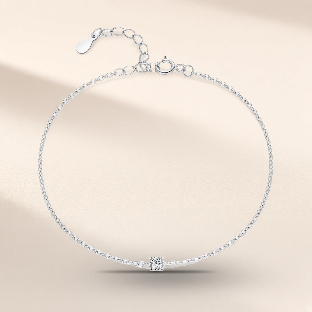 Bracelet Étoile du Berger argent 925, modèle 3 mm : une moissanite synthétique ronde tenue par quatre griffes au milieu d'une chaîne fine, rallonge au fermoir, sur fond crème