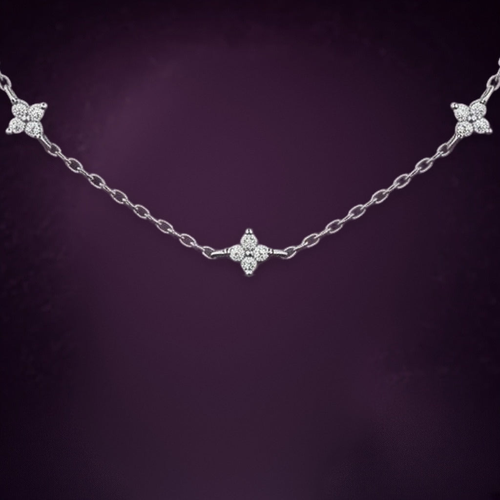 Collier Nuée d'Étoiles en gros plan : trois étoiles à quatre branches serties de petites pierres claires