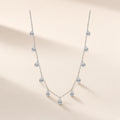 Collier Pluie d'Avril argent 925, chaîne fine semée de gouttes de zirconium cubique incolore, sur fond crème