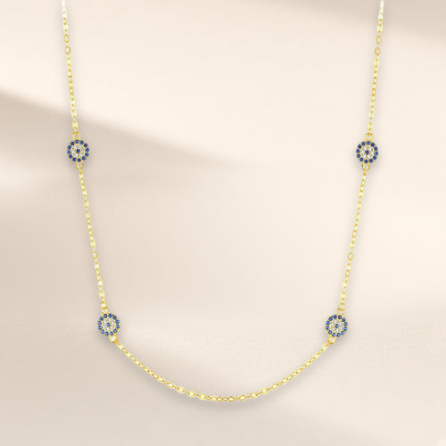 Collier Signe Bleu, finition dorée sur argent 925, modèle quatre médaillons : quatre petits médaillons ronds de pierres d'imitation bleues et claires, espacés sur la chaîne, sur fond crème