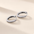 Créoles Liseré argent 925 à charnière, un rang de petites moissanites synthétiques sur la face visible de chaque créole, sur fond crème