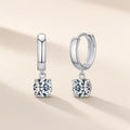 Créoles Source Vive argent 925, moissanite synthétique ronde suspendue sous l'anneau lisse, sur fond crème
