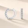 Petites créoles Pléiade argent 925, rang de moissanites synthétiques incolores sur la face visible, sur fond crème