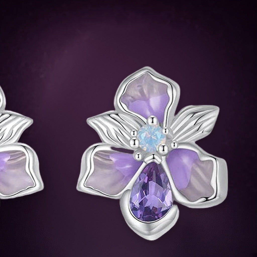Puces Iris du Matin en gros plan : pétales lilas et mauves, petite pierre bleu pâle au cœur et goutte violette