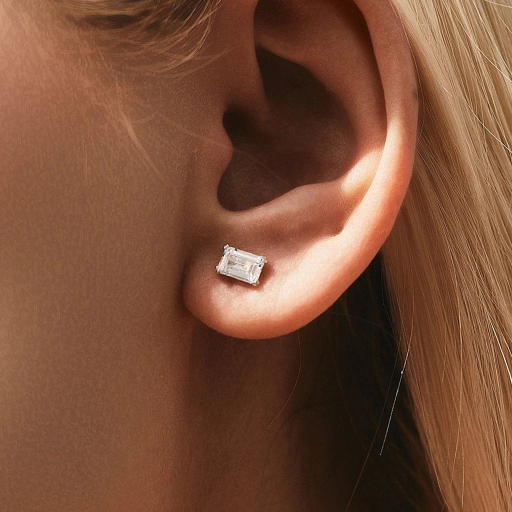 Puces Miroir d'Eau portées à l'oreille : la petite pierre rectangulaire claire sur le lobe